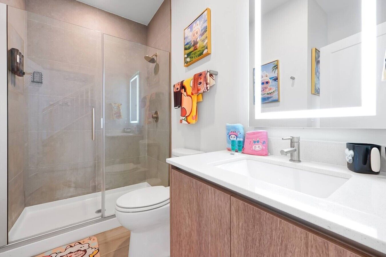 Un baño moderno con cabina de ducha de vidrio, inodoro, lavabo blanco con espejo y un armario.