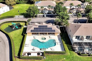 Un immeuble résidentiel doté d’une piscine, de panneaux solaires et d’une pelouse bien entretenue.