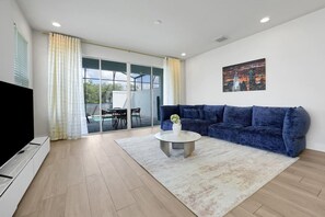 Ein modernes Wohnzimmer mit einem blauen Sofa, einem Couchtisch und einem Fernseher.