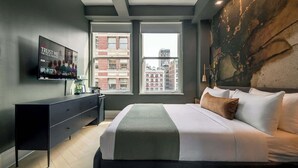 Et moderne hotelværelse med en stor seng, et fladskærms-tv, en kommode og udsigt over byen.