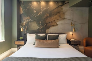 A bedroom with a large bed, two bedside tables, a nightstand, a chair, and a wall with a textured design.