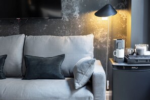 Un soggiorno moderno con un divano grigio, una lampada nera e una macchina da caffè su un tavolino.