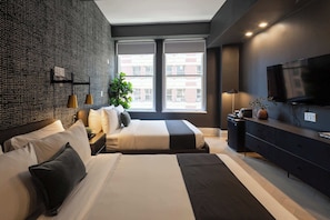Una habitación de hotel moderna con una cama grande, televisión, escritorio y ventana con vista a la ciudad.