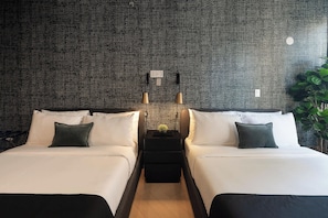 A hotel room with two beds, a nightstand with a lamp, a potted plant, and a textured wall.