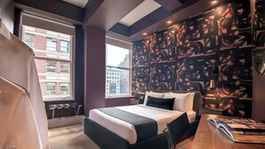 Quarto de hotel moderno com uma cama grande, uma escrivaninha e vista para a cidade.