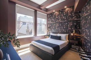 Un dormitorio moderno con una cama grande, dos ventanas y una vista a la ciudad, además de un cuadro abstracto en la pared.