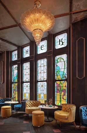 Een kamer met een kroonluchter, glas-in-loodramen en gestoffeerde meubels.