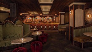 A bar area with a wooden ceiling, bar counter, and seating with round tables and red upholstered chairs. - NoMad Hotel Near Broadway & 5th Ave (New York)