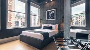 A modern hotel room with a large bed, a small sofa, a city view, and a framed picture on the wall. - Madison Square Studio at Return Policy Broadway (New York)