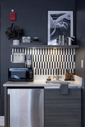 Een moderne keuken met een koffieapparaat, magnetron en een koelkast van roestvrij staal.