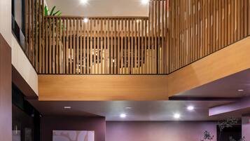 Un área de recepción moderna con un mostrador de madera, una mesa redonda y un espacio de espera con un banco acolchado.