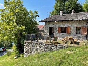 A stone house with a tiled roof, a stone wall, and a metal fence. - La Baita dei Nonni by Interhome (Gera Lario)
