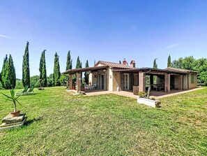 Une maison avec un patio, un espace salon extérieur et une pelouse.