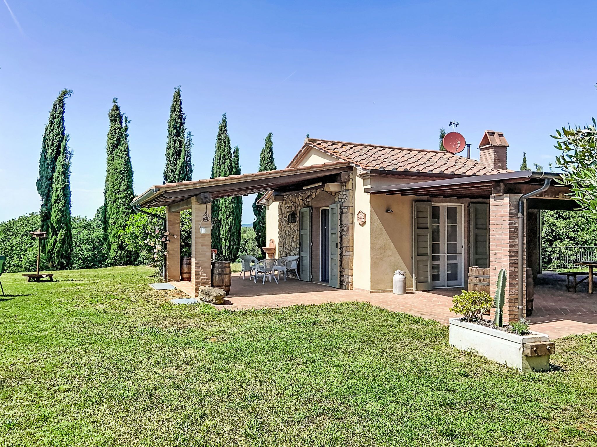 A house with a patio, stone walls, and a covered seating area.