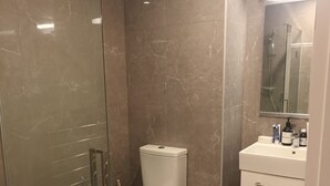 Une salle de bain avec une douche à parois de verre, des toilettes et un lavabo avec un miroir au-dessus.