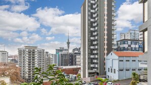 Un immeuble de grande hauteur doté de nombreux balcons, entouré d’autres bâtiments et surplombant un ciel dégagé.