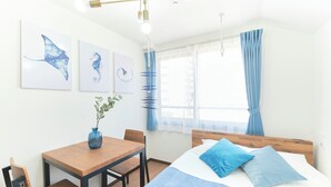 Une chambre à coucher avec un lit, une table en bois, des chaises et des œuvres d’art accrochées au mur.
