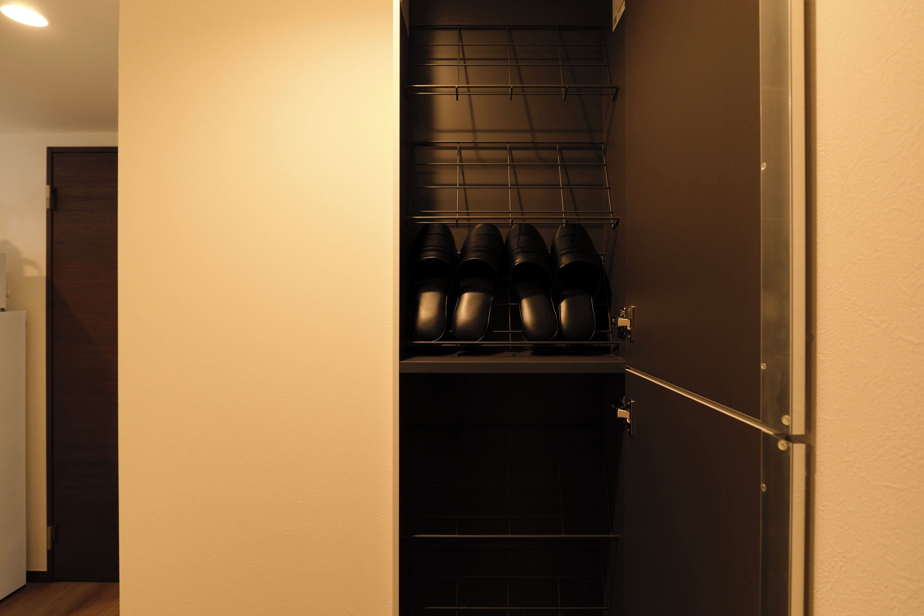 A hallway with a shoe rack and a door.