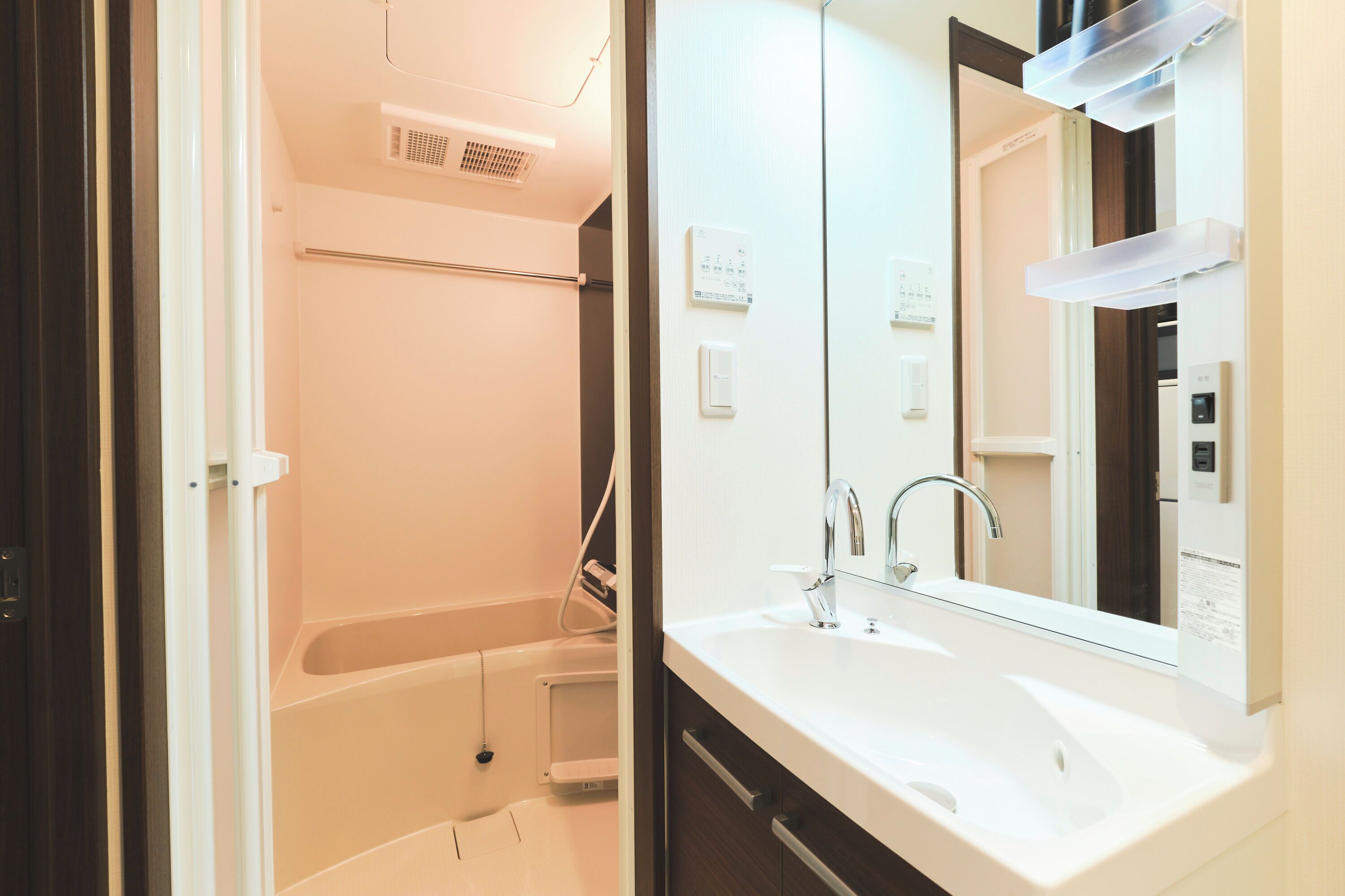 A modern bathroom with a white sink, a mirror, and a shower area.