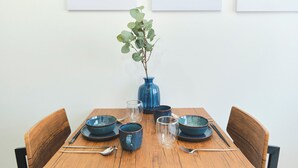 Une table à manger avec des bols, des verres et des baguettes en céramique bleue, entourée de chaises en bois.
