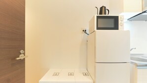 A compact kitchen with a microwave, a small refrigerator, and a white cabinet with a door handle. - Fuente Nishi Sugamo by Tranova 2 (Toshima)