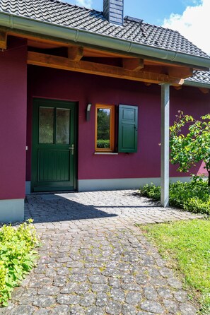 Un bâtiment avec une porte verte, une fenêtre et un toit recouvert de tuiles.
