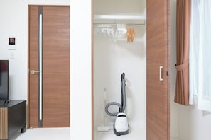 Ein Zimmer mit Holztür, Staubsauger, Handtuchhalter und Vorhang.
