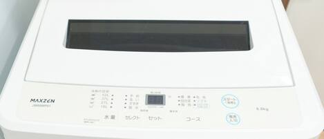 A white washing machine with Japanese labels, a digital display, and a control panel with buttons.