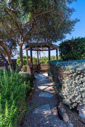 A garden pathway leading to a wooden pergola structure surrounded by lush greenery and a clear blue sky. - Villa Pine View -  a villa that sleeps 6 guests  in 3 bedrooms (Argaka)