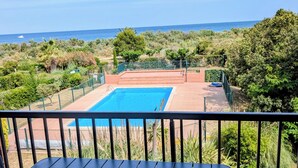 Ein Pool mit Meerblick, umgeben von viel Grün.
