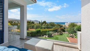 Un balcón con vistas a un jardín ajardinado y al mar.