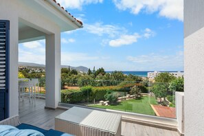 Ein Balkon mit Blick auf einen angelegten Garten und das Meer.
