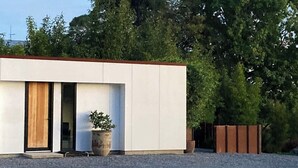 Moderni rakennus, jossa on tasakatto, suuret ikkunat ja sorapäällysteinen ajotie.