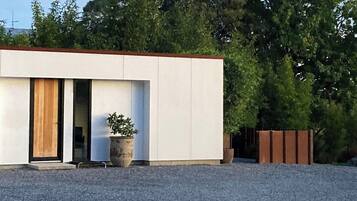 A modern building with a flat roof, large windows, and a gravel driveway.