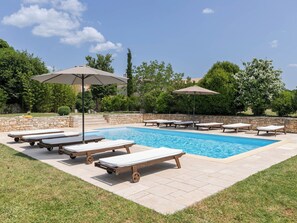 A swimming pool with lounge chairs and umbrellas, surrounded by stone walls and greenery. - Vacation home Altona by Interhome (Barbariga)