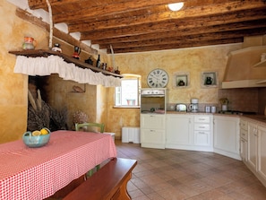 A rustic kitchen with a wooden ceiling, white cabinets, a red and white checkered tablecloth, and a vintage clock. - Vacation home Altona by Interhome (Barbariga)