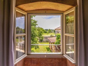 A room with a large window overlooking a garden and a stone building. - Vacation home Altona by Interhome (Barbariga)