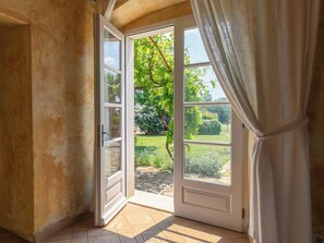 Eine offene Tür, die in einen Garten mit einem gepflasterten Weg und viel Grün führt.