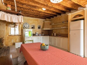 A kitchen with wooden beams, white cabinets, a red checkered tablecloth, and a clock on the wall. - Vacation home Altona by Interhome (Barbariga)