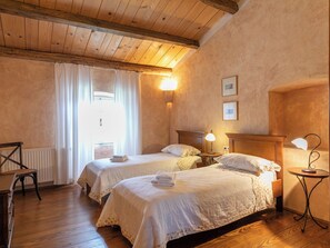 A room with two beds, a wooden ceiling, a radiator, and a table with chairs. - Vacation home Altona by Interhome (Barbariga)