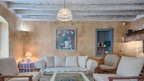 Una sala de estar rústica con un sofá, sillones, una mesita de centro, un cuadro y una estantería.