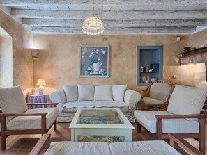 Ein rustikales Wohnzimmer mit einer Couch, Sesseln, einem Couchtisch, einem Gemälde und einem Bücherregal.