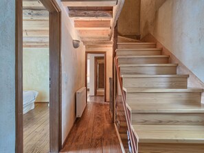 Eine Holztreppe führt zu einem Schlafzimmer mit einem Bett und einer Heizung.