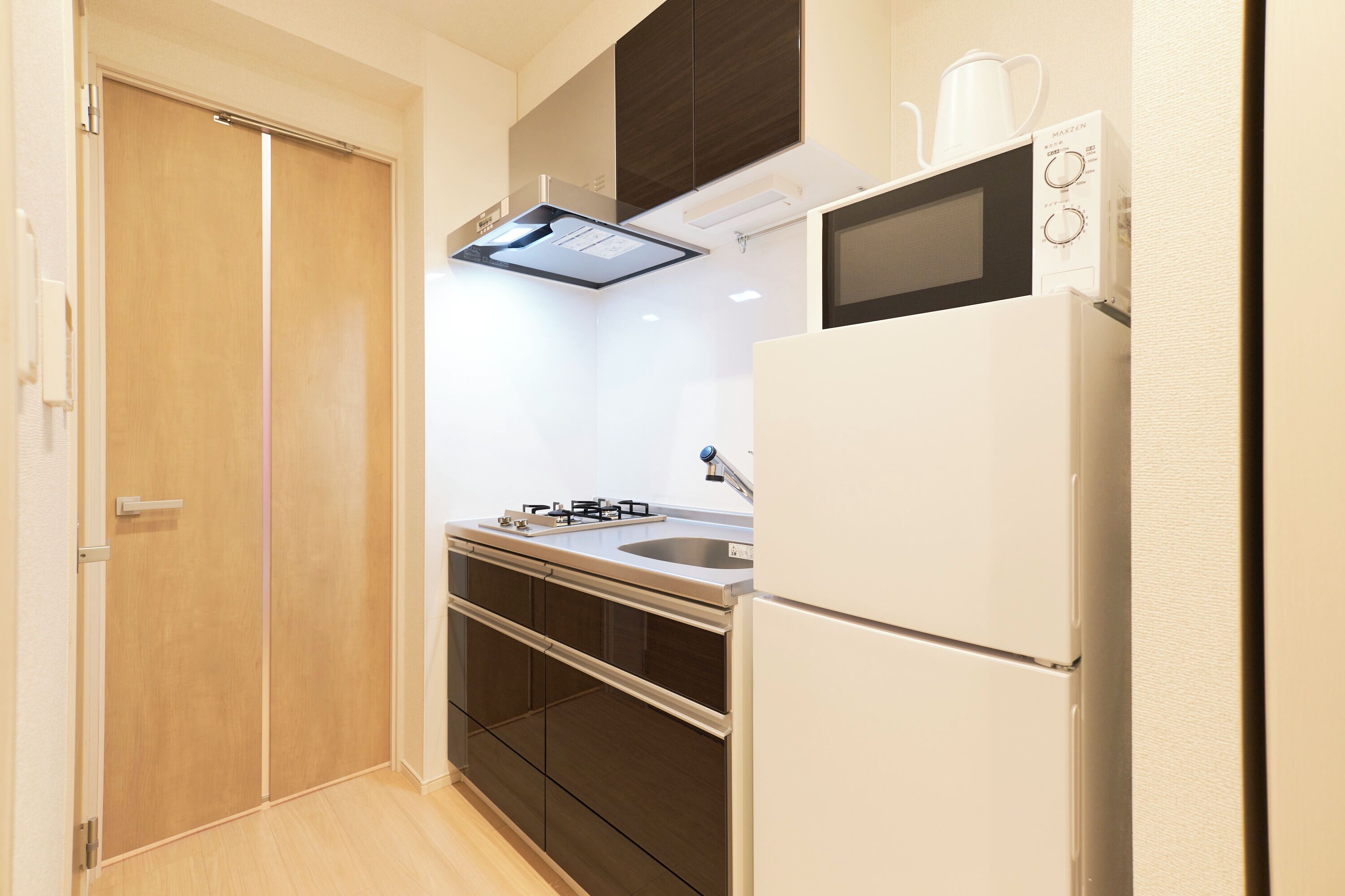 A compact kitchen with a refrigerator, microwave, and stove.