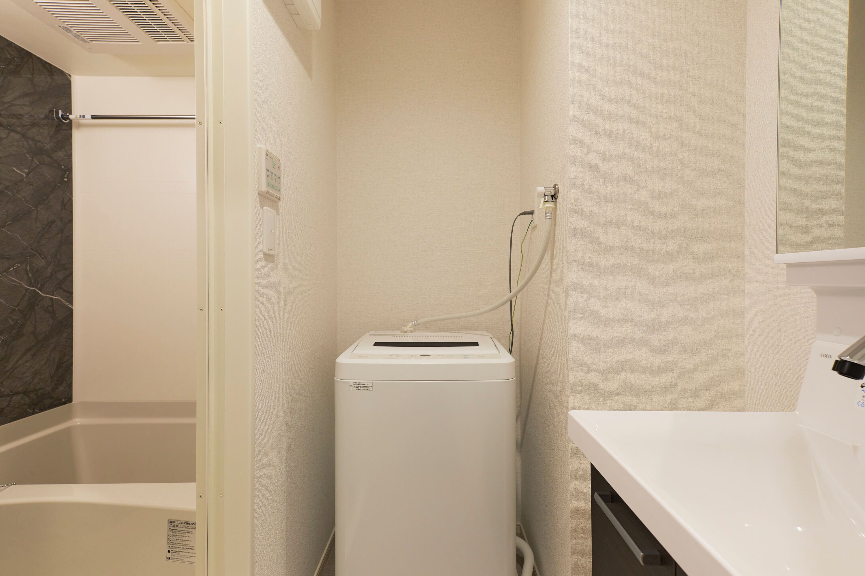 A compact bathroom with a white sink, a towel rack, a shower area, and a built-in dryer.