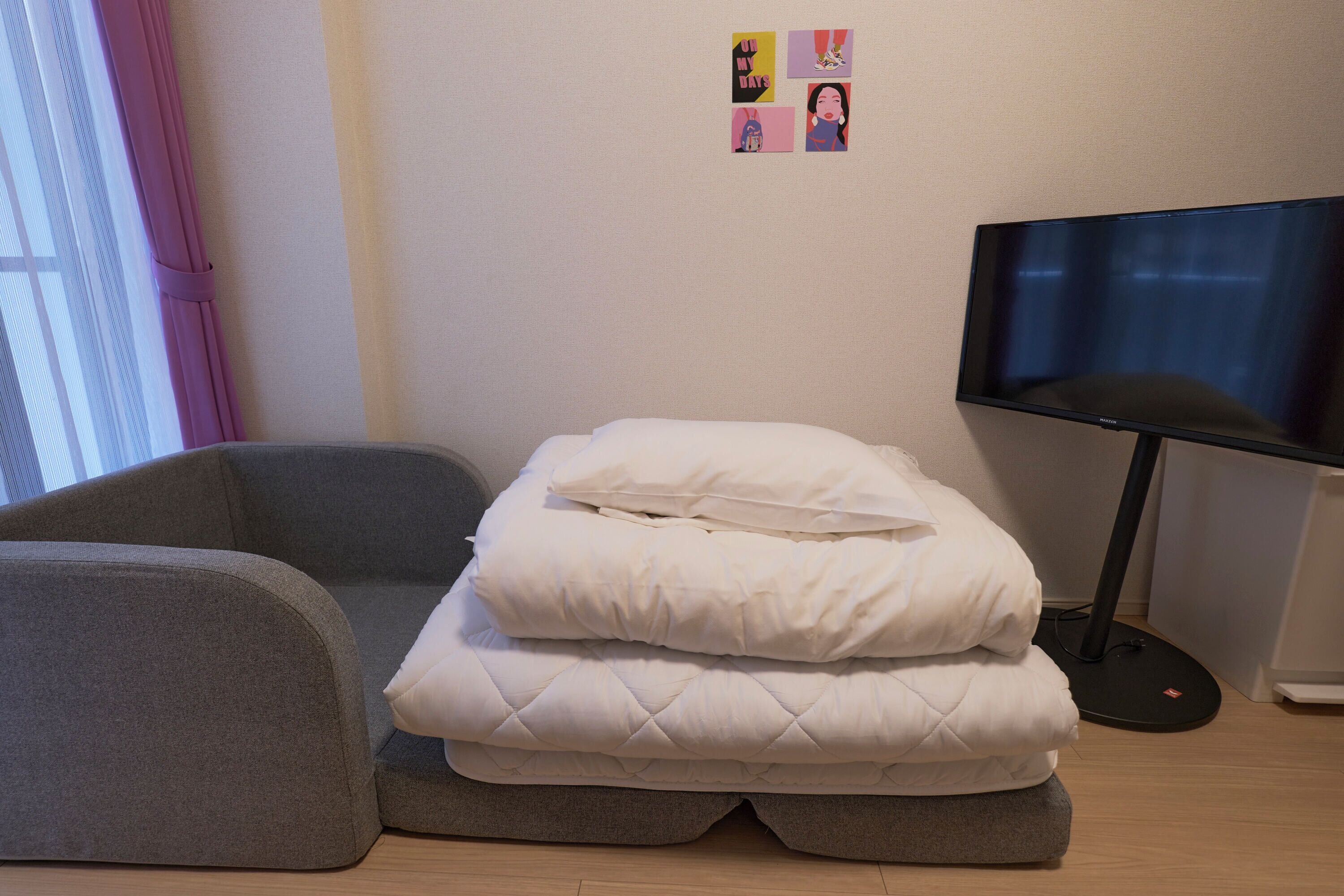 A room with a bed, a television, and a window with curtains.
