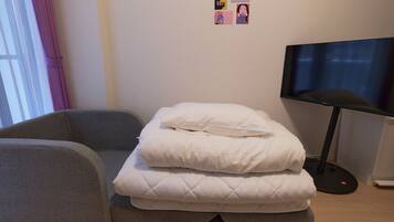 A room with a bed, a television, and a window with curtains.