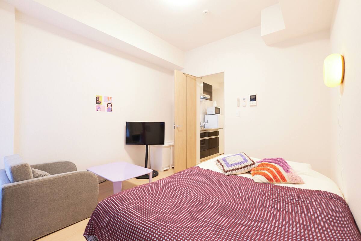 A hotel room with a bed, a sofa, a television, and a desk.