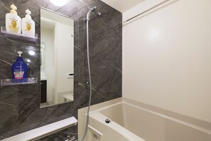 A bathroom with a bathtub, a shower, a marble wall, and a mirror. - G-stage 01 IKEBUKURO 2 by Tranova (Toshima)