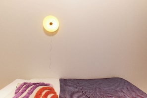 Ein Bett mit einem gemusterten Überwurf und einer Wandleuchte.